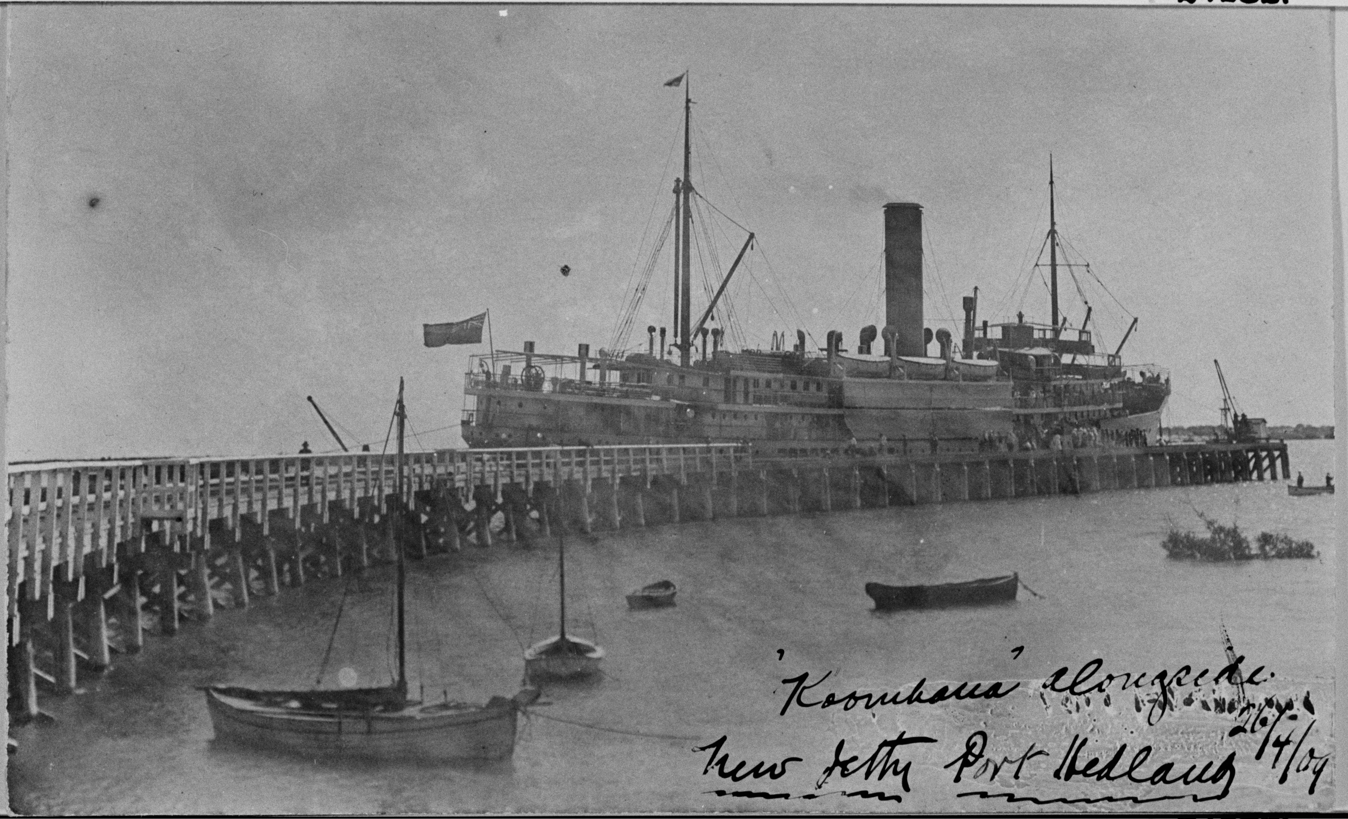 Steam ship behind a curved jetty.