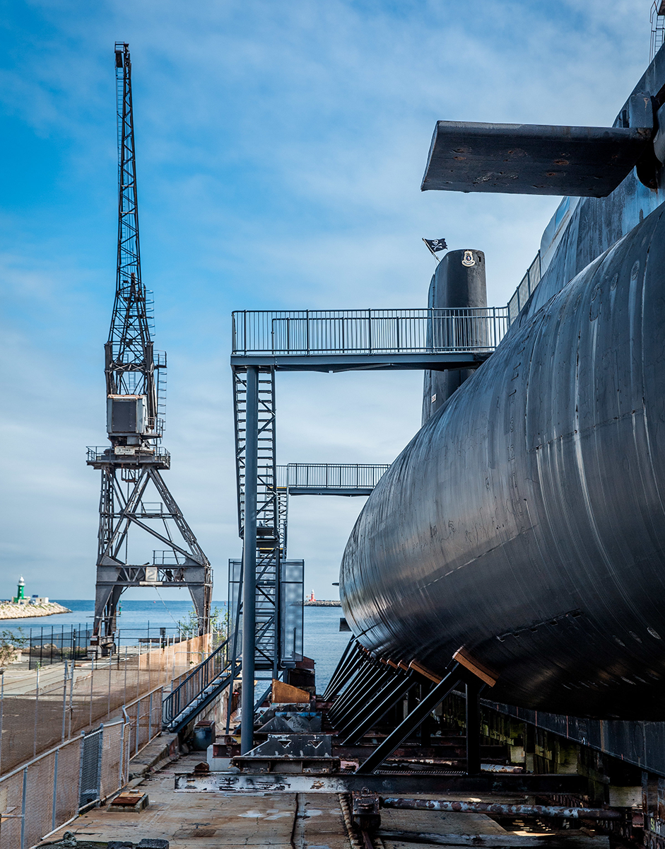 An exterior view of the submarine HMAS Ovens and surrounding slipway beneath a blue sky