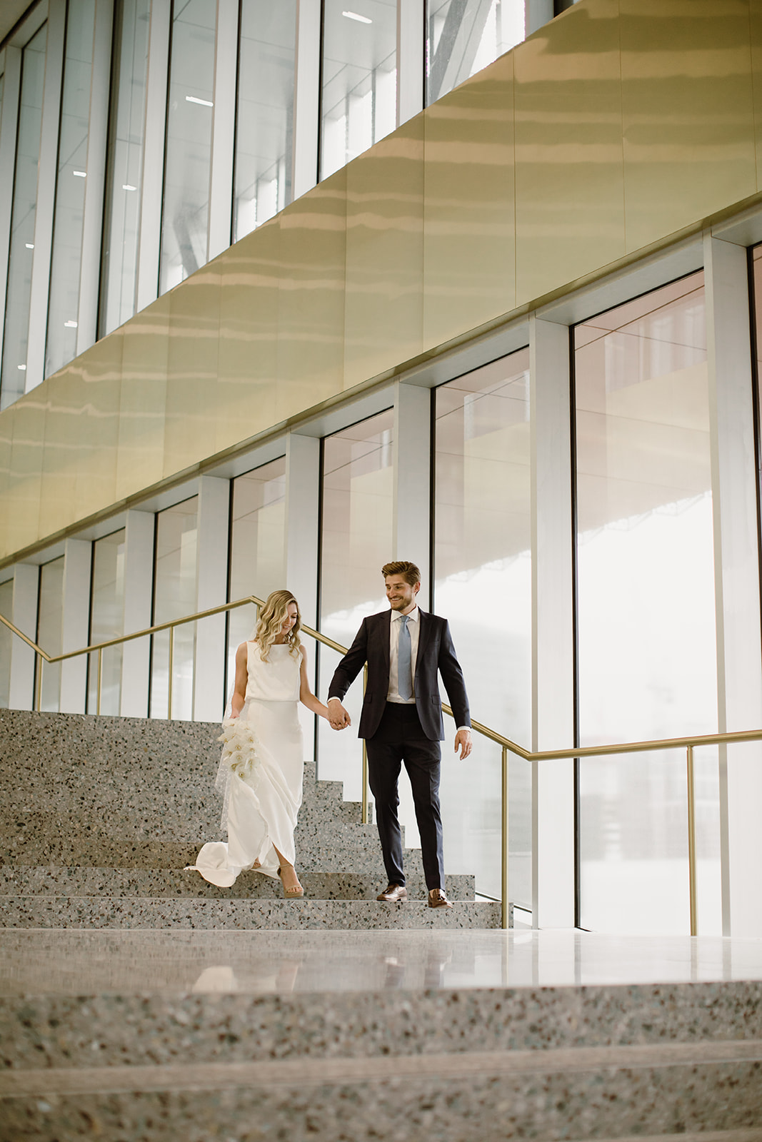 2 people in wedding outfits walking down stairs