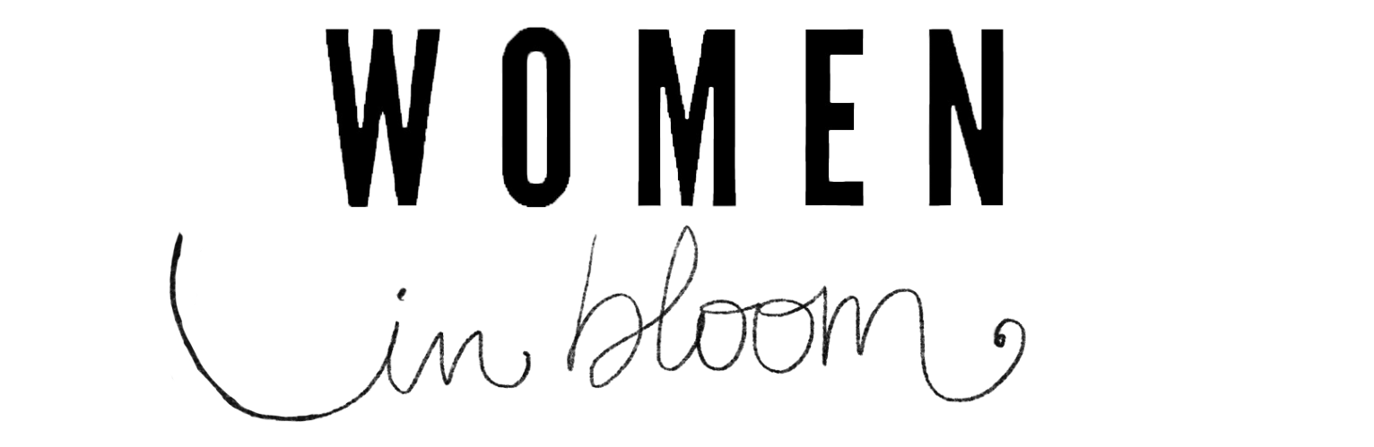 A logo for the Women in Bloom exhibition with the word WOMEN in large black bold captial latters and the words In Bloom in a hand-drawn, cursive style