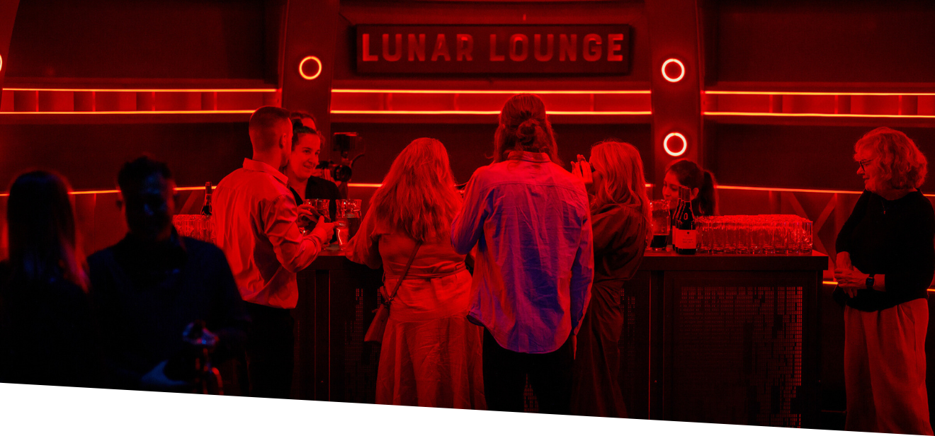 Lunar Lounge pop-up bar, red lighting around and a few people waiting to order drinks
