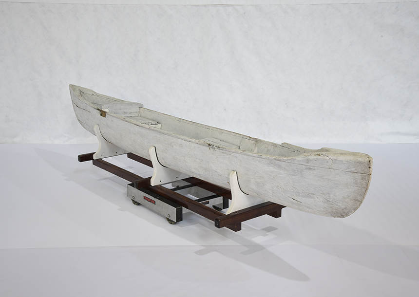 This double outrigger canoe was likely constructed from a single piece of hollowed Gyrocarpus Americanus wood and painted white. It comes with two booms, to which two floats can be attached. One float is broken. The vessel features two loose seats, one with a back rest. The floats are slipped in metal stirrups and wired on. 