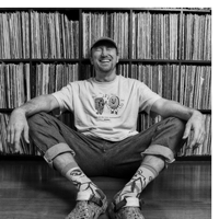 a person sits on the floor with music records in the background