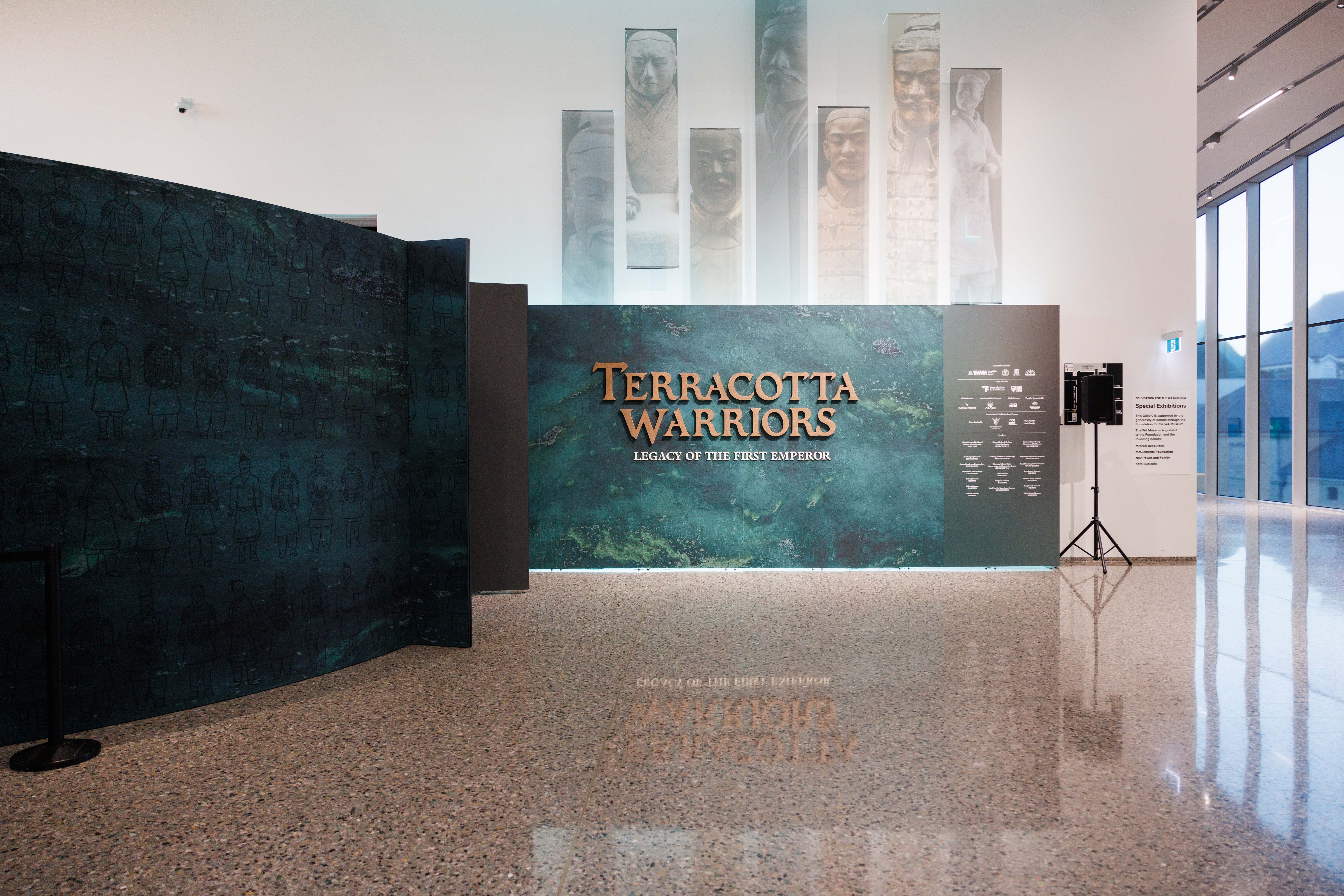 Exhibition display with "Terracotta Warriors: Legacy of the First Emperor" sign on a teal backdrop.