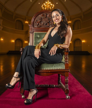Simone Craddock on a Chair in a hall with red carpet