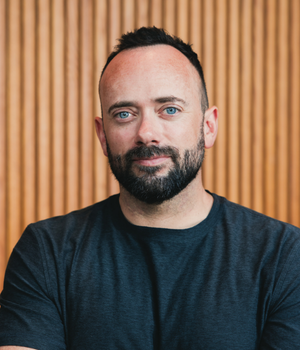 Man with beard in navy tshirt with wood background