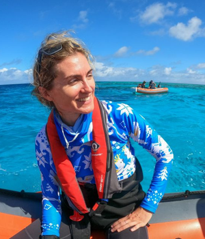 Lady in a blue shirt with a life vest on a boat.