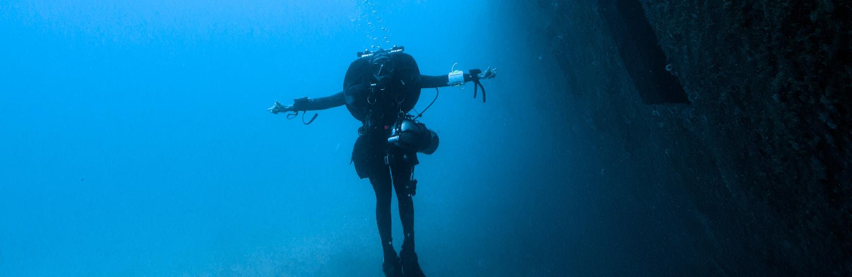 Underwater photo of a man diving next to a submerged ship