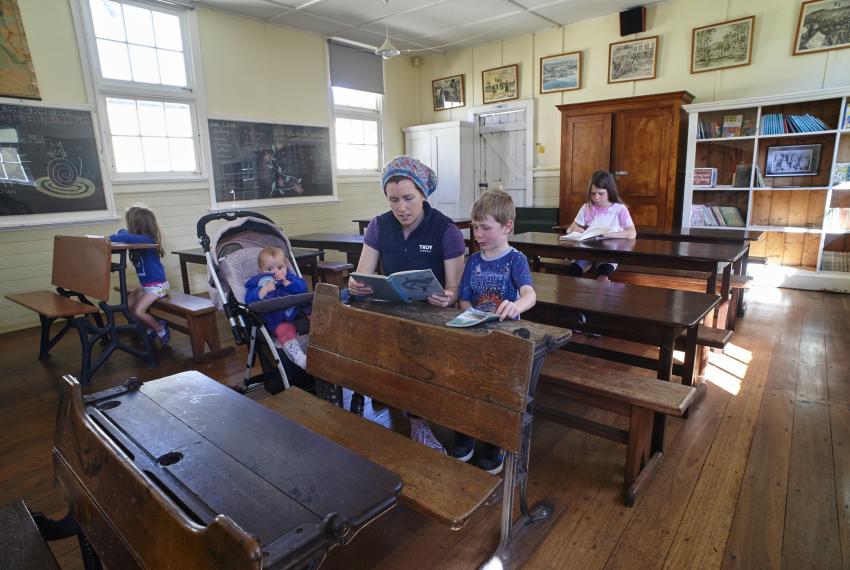 People sit in the school room at the Museum of the Great Southern