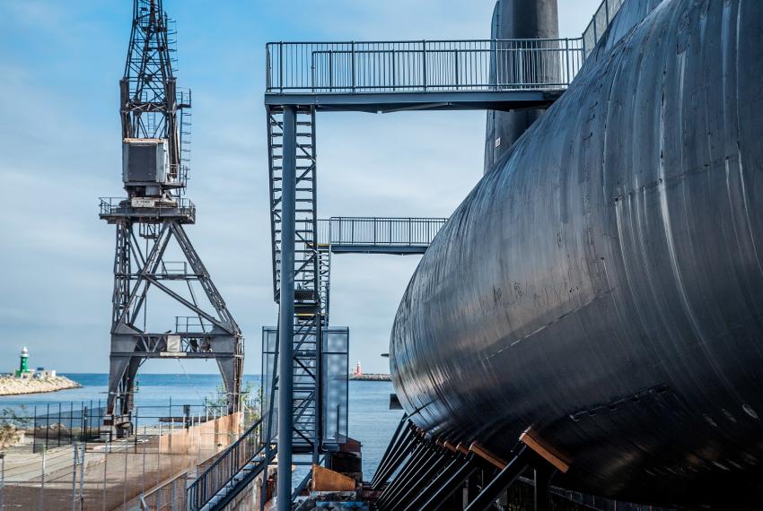 An exterior view of the submarine HMAS Ovens and surrounding slipway beneath a blue sky