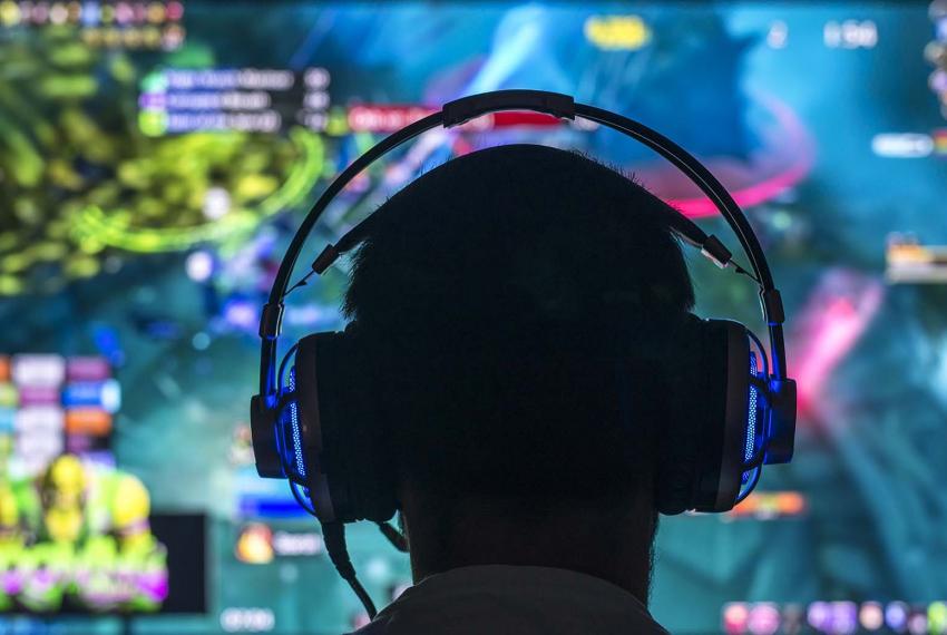 A photograph of a person wearing headphones standing in front of a screen