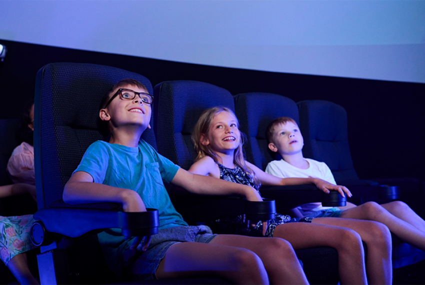 3 children sitting in a cinema smiling