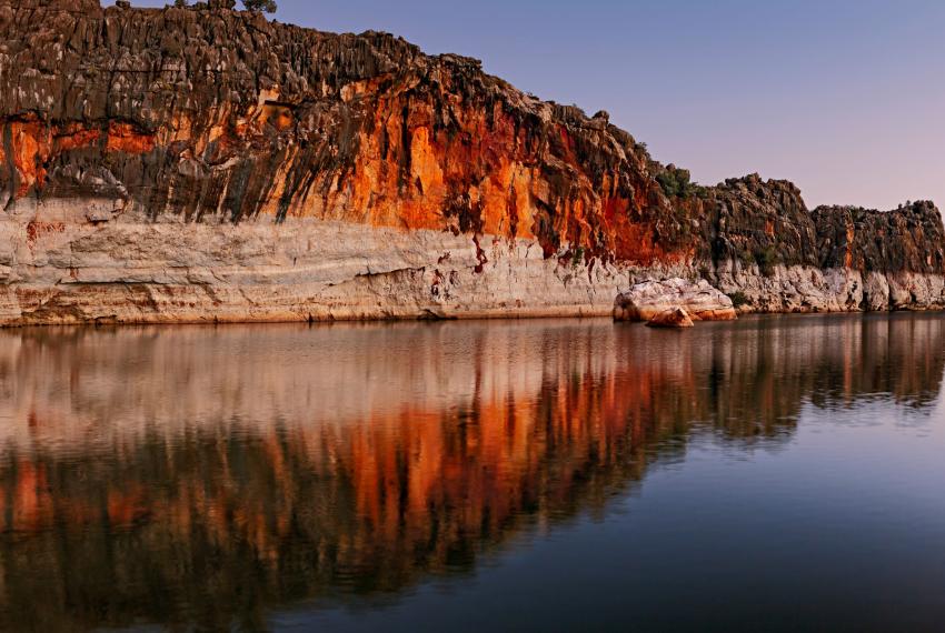 Danggu Geikie Gorge Twilight, a cliff face going into the river at sunset, with reflections on the water