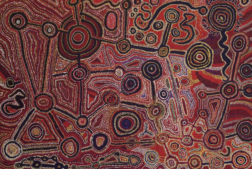 A Native Title Painting featuring an array of colourful painted dots in deep reds and blues and bright oranges yellows and purples in the shapes of concentric circles and interconnected lines 