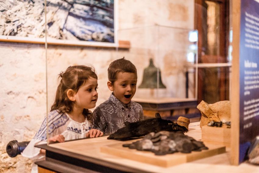 Two small children examining a museum exhibition behind a glass case
