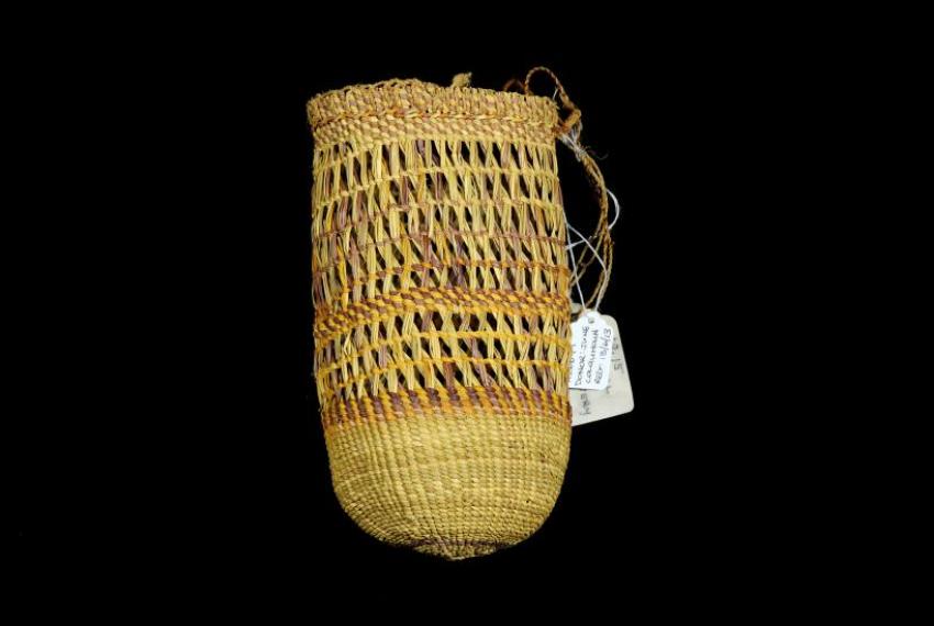 A woven dilly bag displayed on a black background