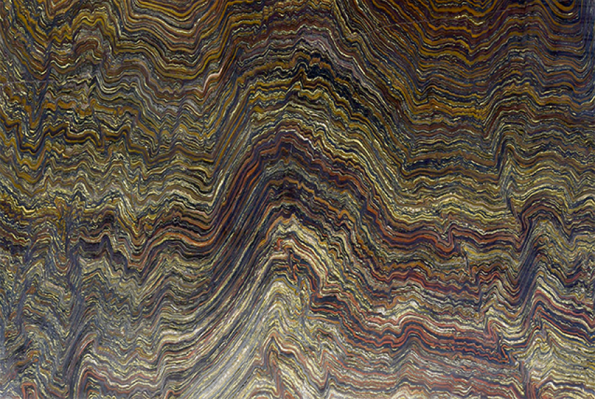 A close up image of Banded Iron Formation, with wavy red, gold and brown layers of rock