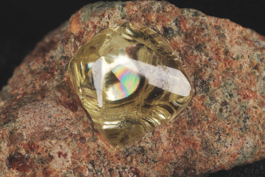 A yellow diamond entrapped in an orangey-brown rock