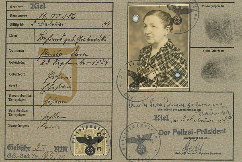 An Identity Card for Juden Pass, complete with various identification information and a photograph of a person with their hair pulled back, wearing a checked garment