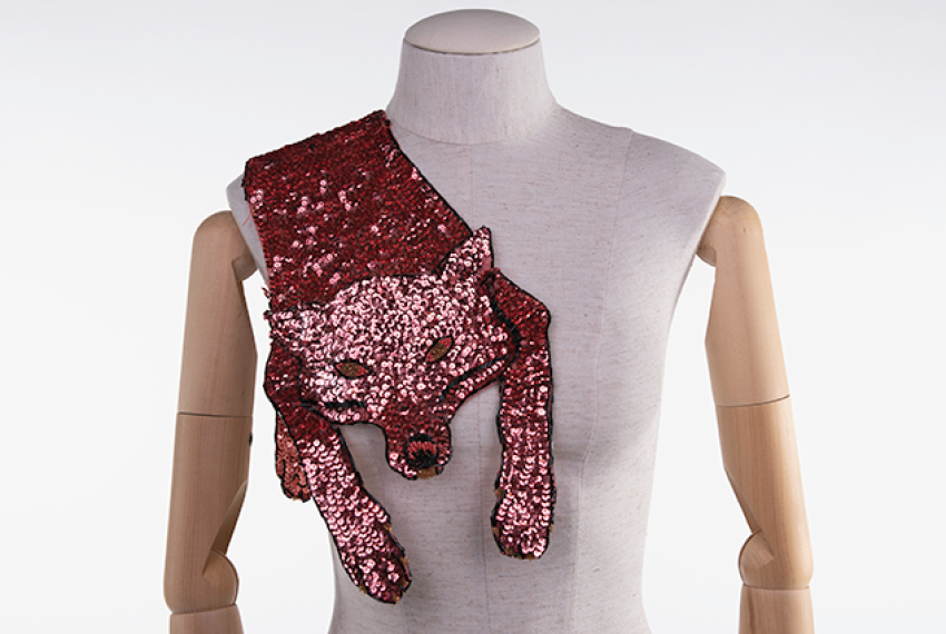 A pink sequinned fox garment hangs over the shoulder of a mannequin.