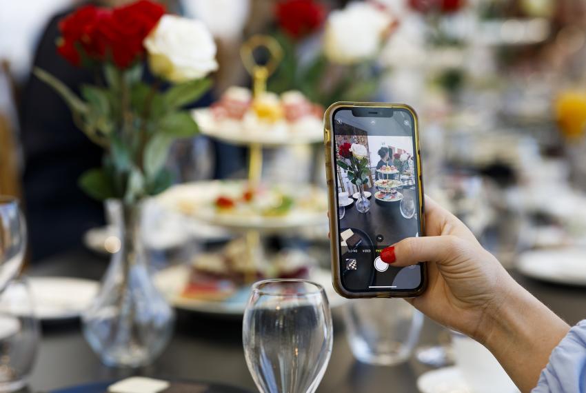 a high tea setup with someone using a phone camera and taking a picture