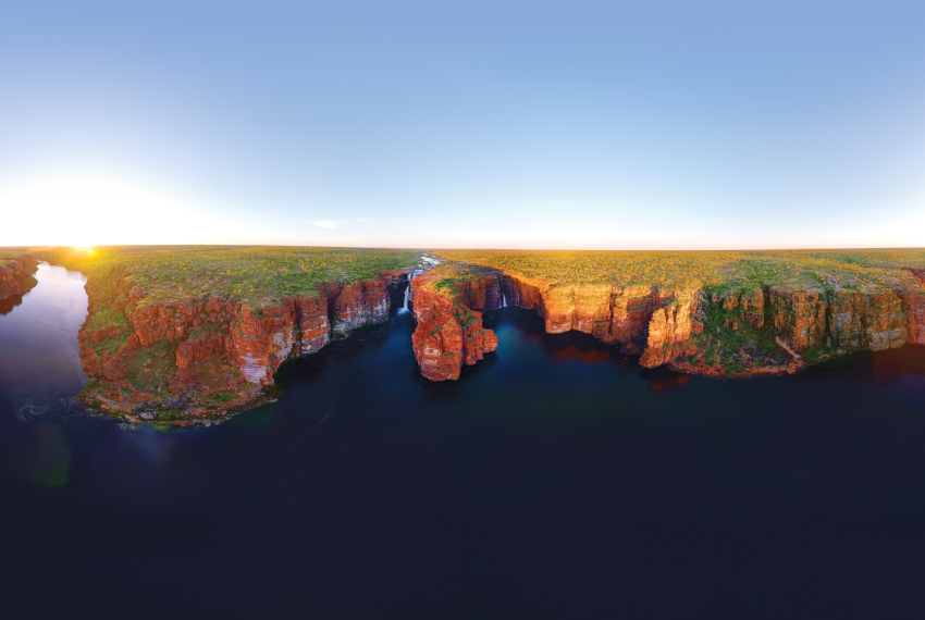 a landscape with ocean in the foreground and cliffs with waterfalls