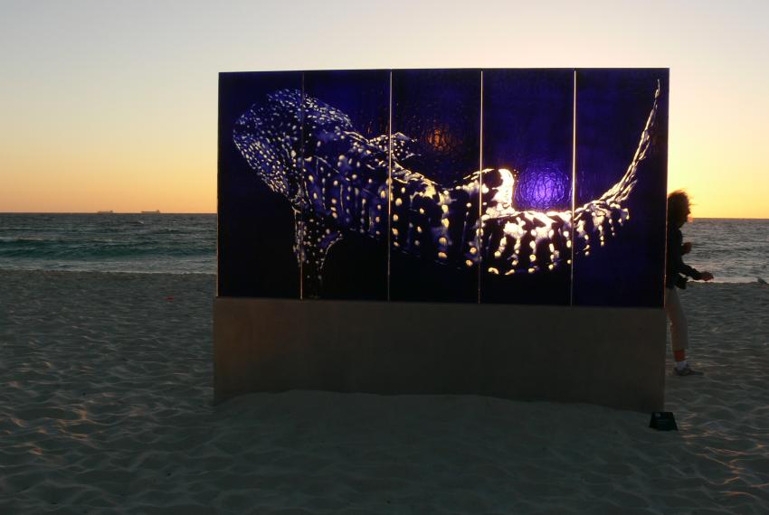 A glass sculpture on display at a beach at sunset
