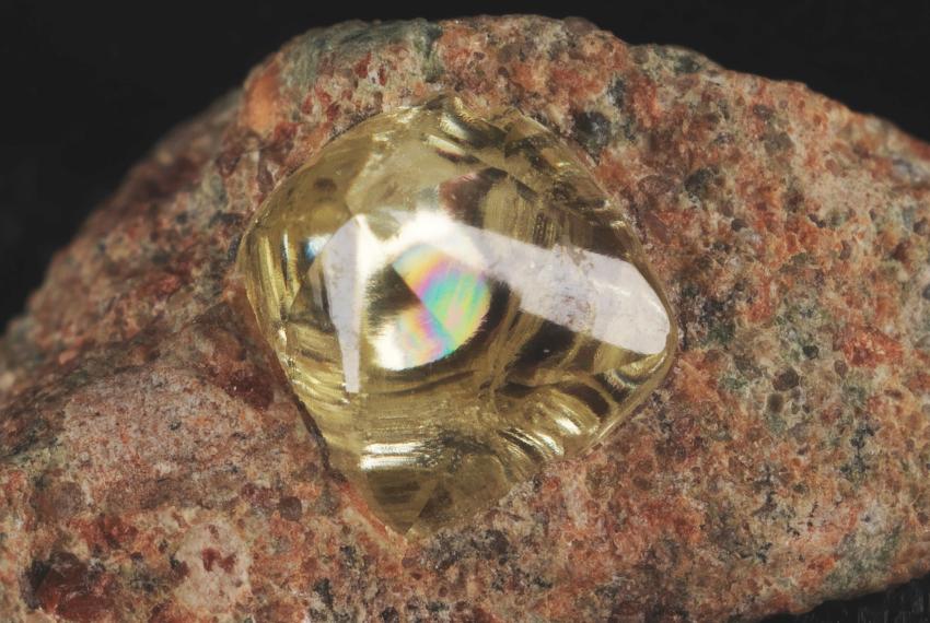 A yellow diamond trapped within a red and brown speckled rock