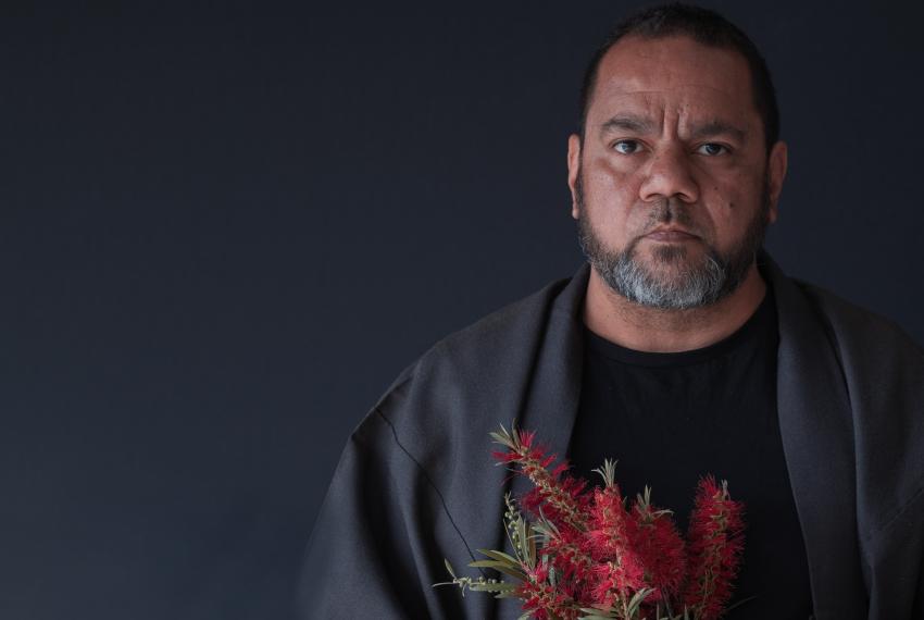 Portrait of an Aboriginal man holding a native Australian bottlebrush