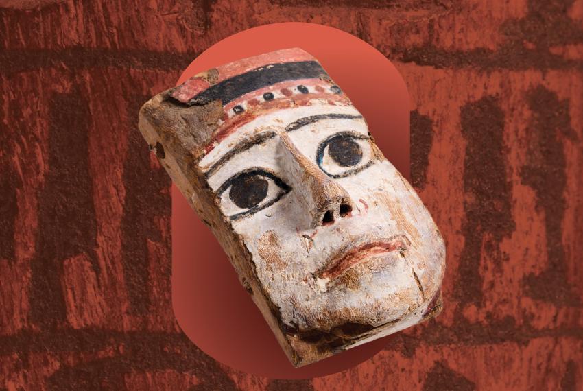 a painted mask object on a background of hieroglyphics