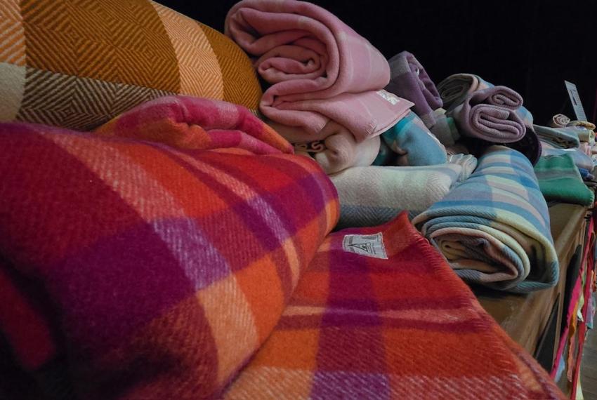 a pile of rolls of woollen fabrics of all colours 