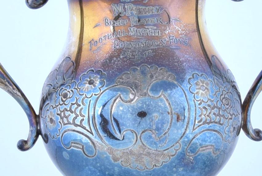 A close-up shot of the trophy engraved with 'Won by M. Perry. Best Player Football Match Economic v Foys.'