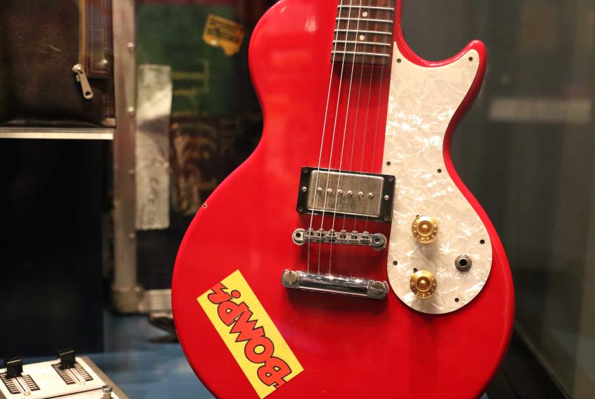 A red Gibson Melody Maker displayed in a glass cabinet in our Reflections Gallery.