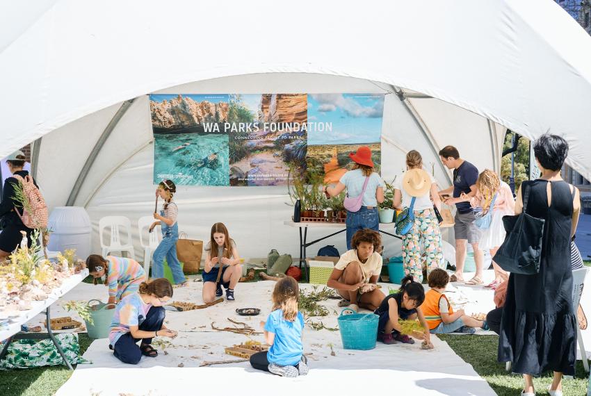 People engaged in outdoor activities under a white tent featuring a "WA Parks Foundation" banner.