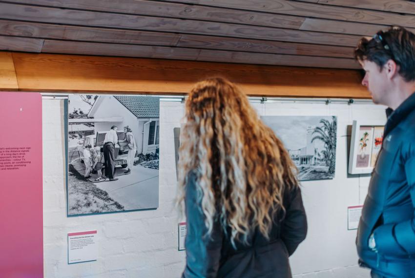 A man and a woman look at a black and white vintage photograph on a Museum wall.