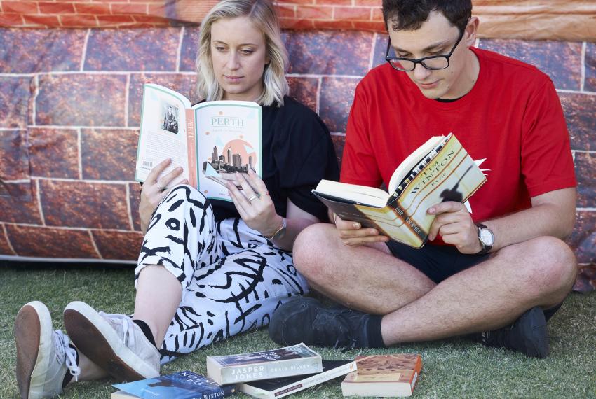 A man and woman reading books about Western Australia