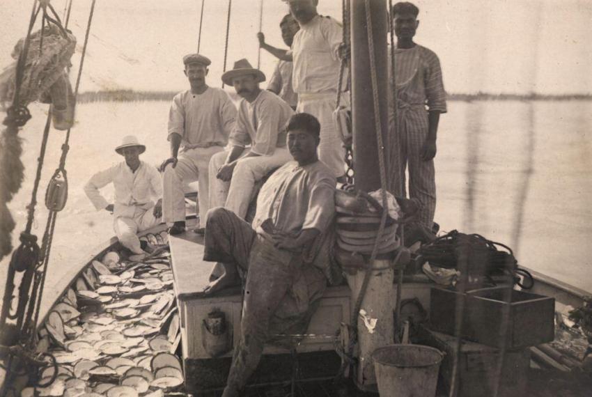 Seven men on a pearl lugger with pearlshells on the deck