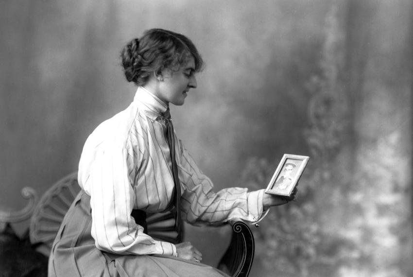 An image of a seated lady observing a portrait picture.