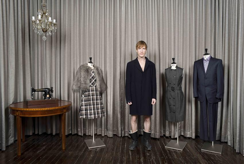Man photographed next to clothes on mannequins