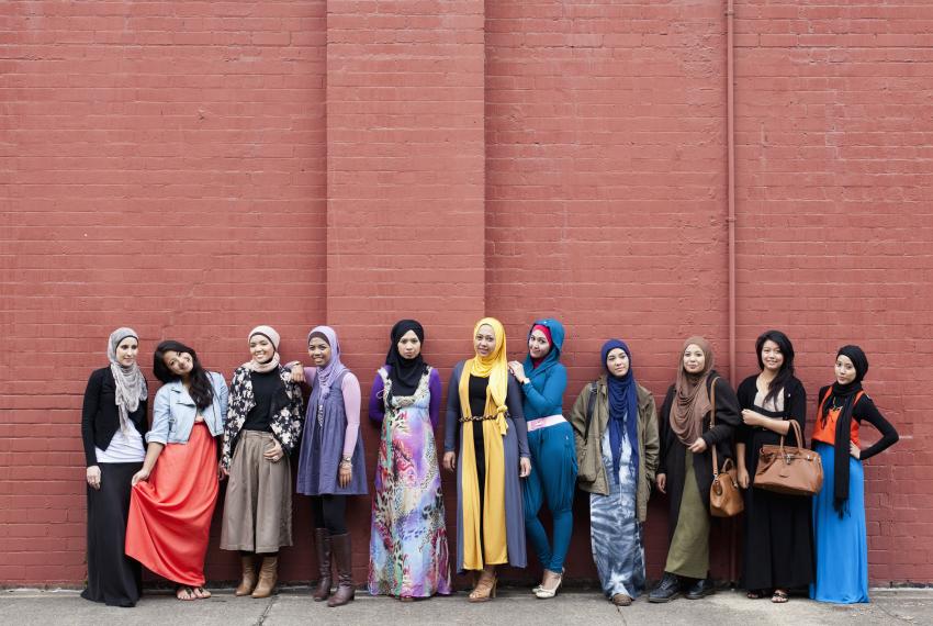 A group of Muslim women standing in front of a brick wall