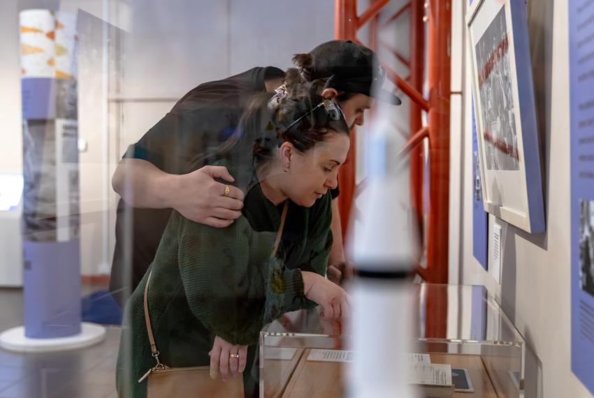 Two people look closely at a collection item from the Out of this World exhibition