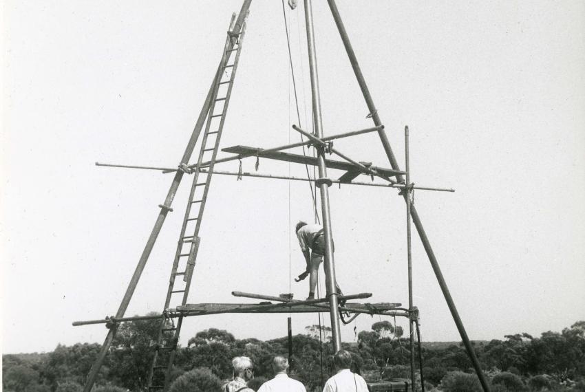 A black and white picture from the early 1960s of a large wooden drilling frame