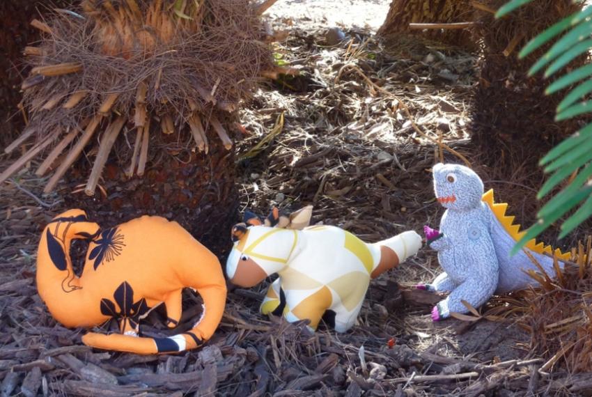 Dinosaur stuffed toys under a tree in a garden