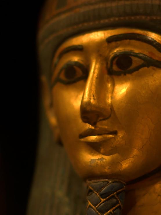 The face of an ancient Egyptian represented in gold on a sarcophagus with painted details