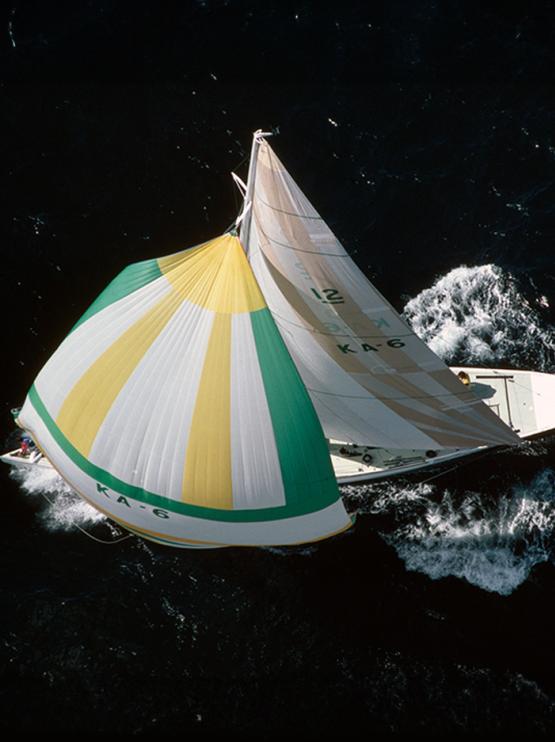 Overhead shot of a yacht with white, green and yellow colours sail in the water 