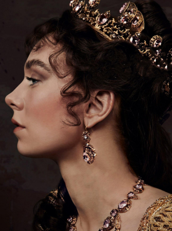 a profile of a woman wearing a crown and jewels with brown curly hair