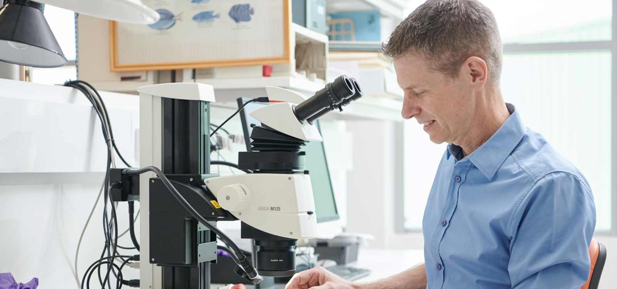 A man looking at a dried sea creature. He is smiling. 