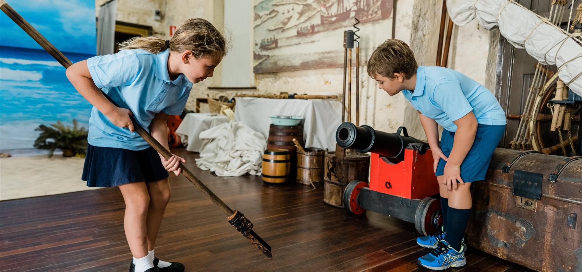 Two children load a small ship's cannon