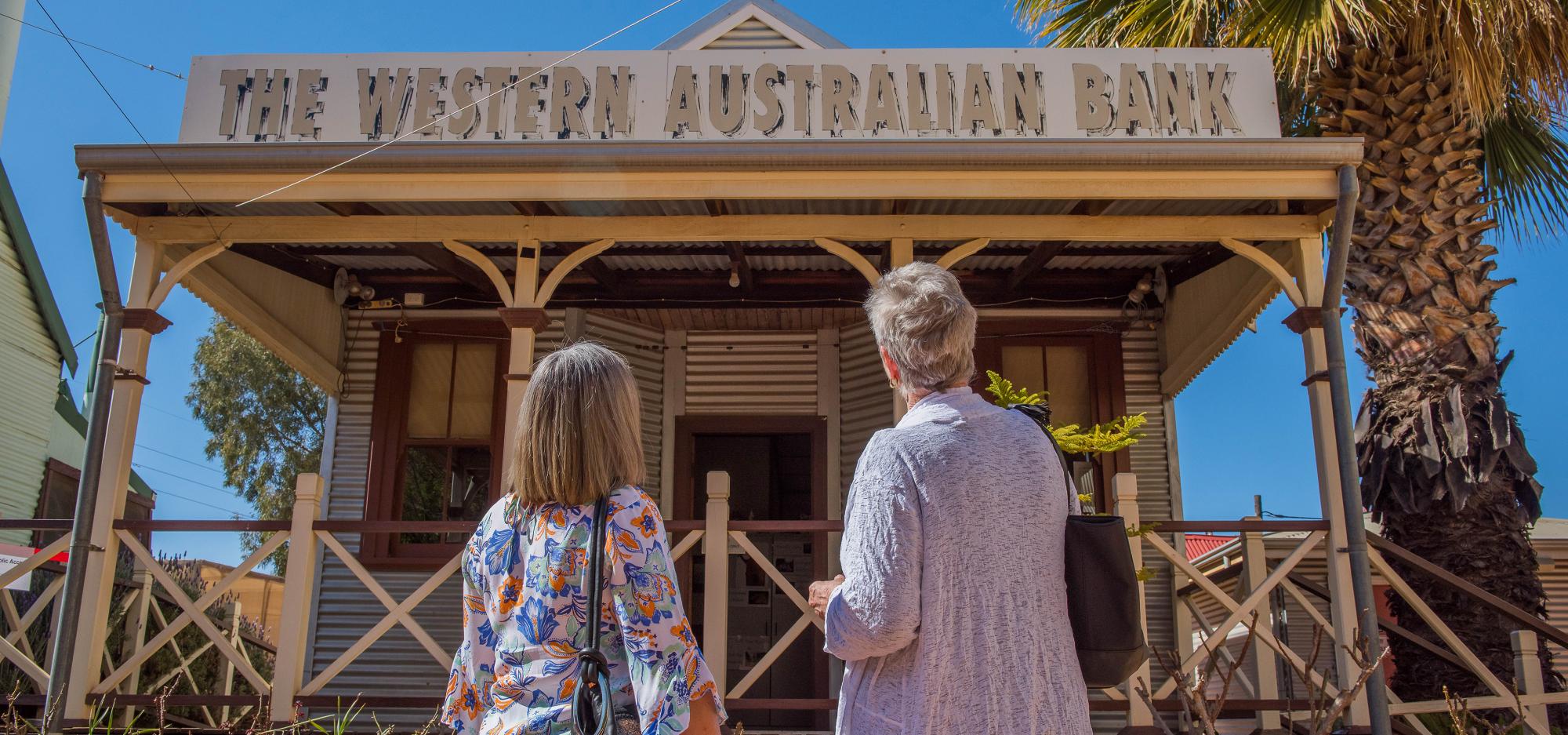 Two people look up at an old bank at the Museum of the Goldfields