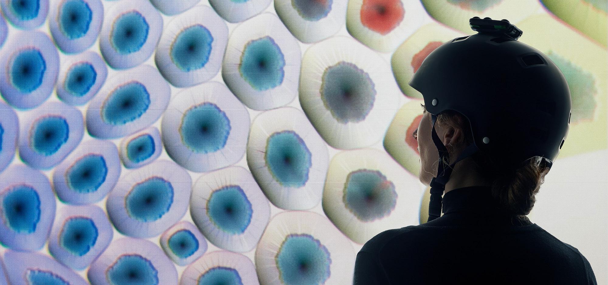 A person wearing a digital headset looks at a screen full of projected colours